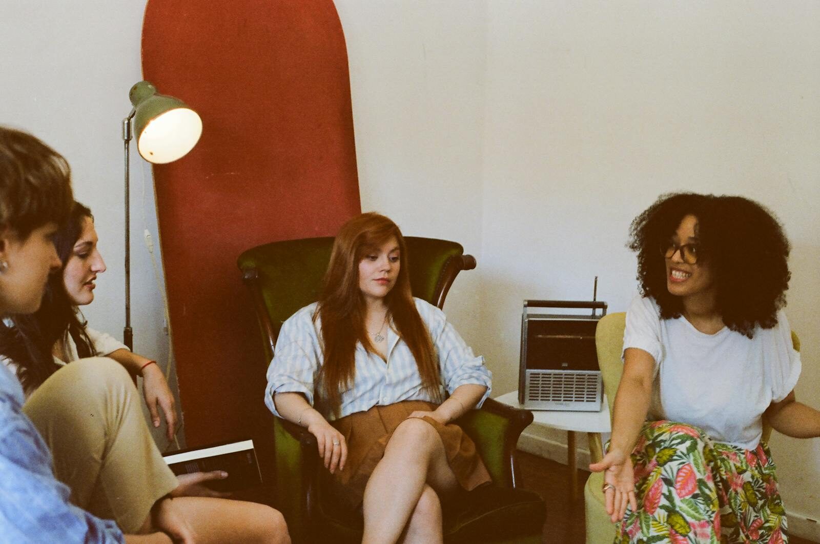 Four adults engaged in a relaxed group discussion in a cozy indoor space.